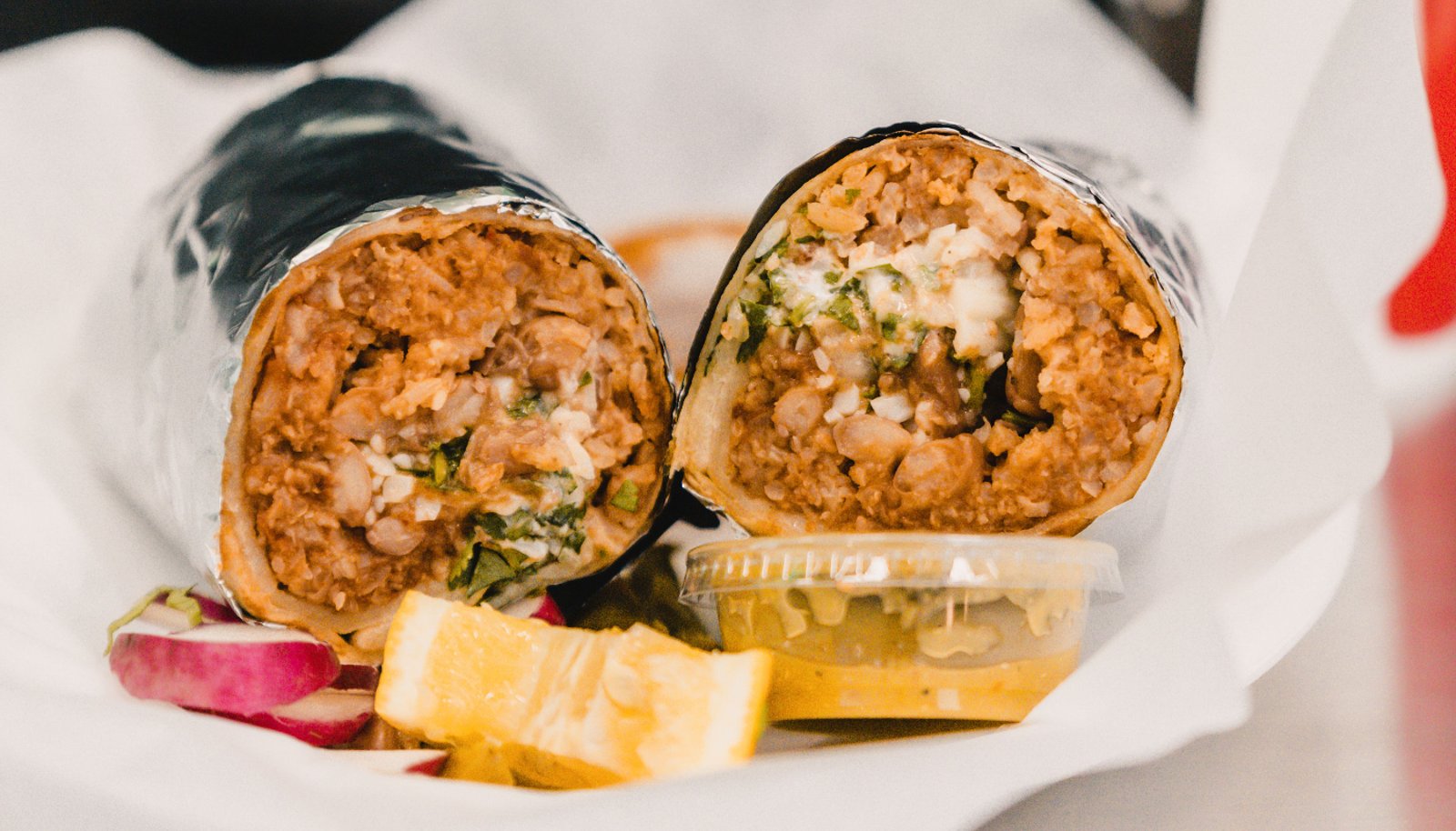 A burrito cut in half showing beans, rice, meat and cheese
