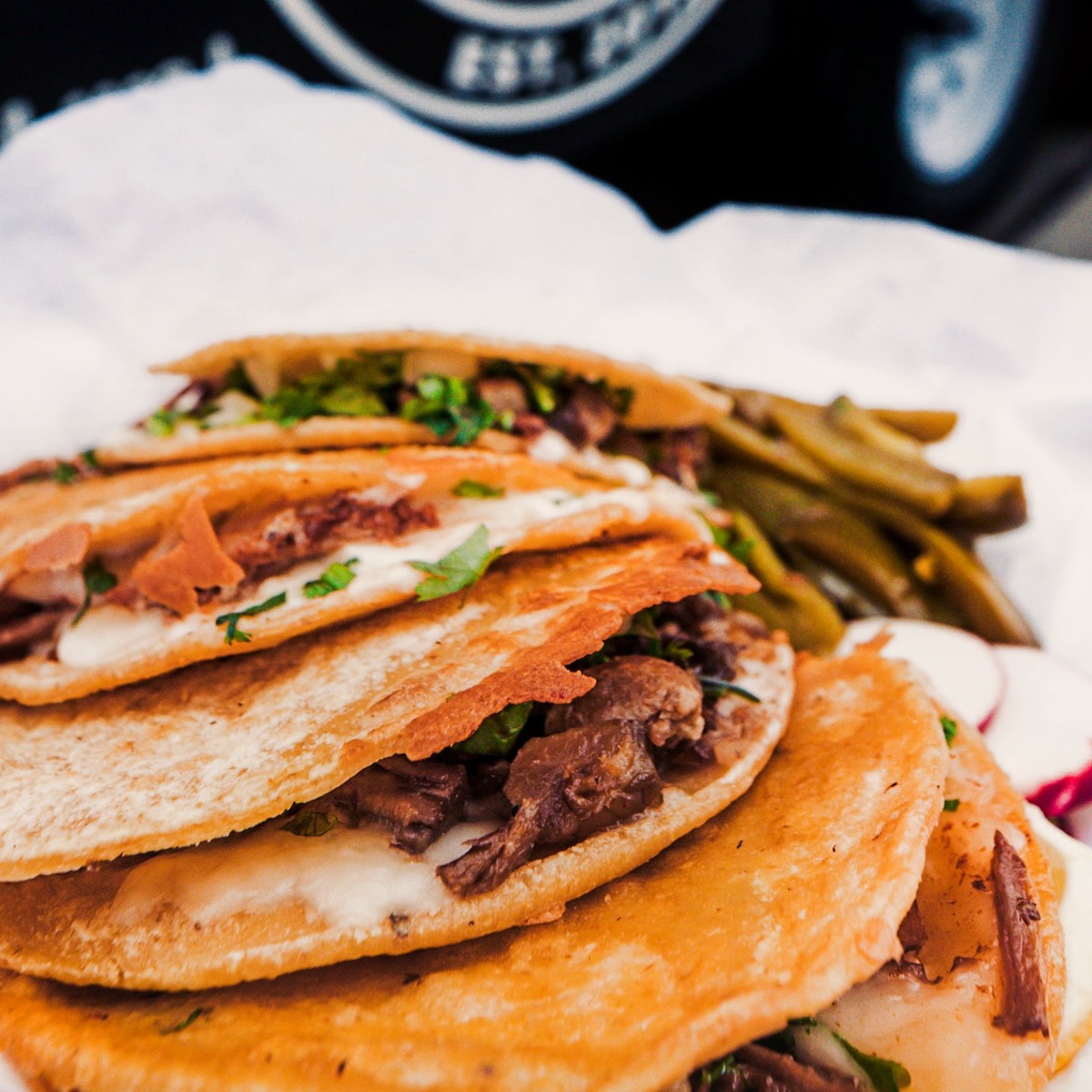 A basket of tacos with melted cheese, cilantro and grilled peppers