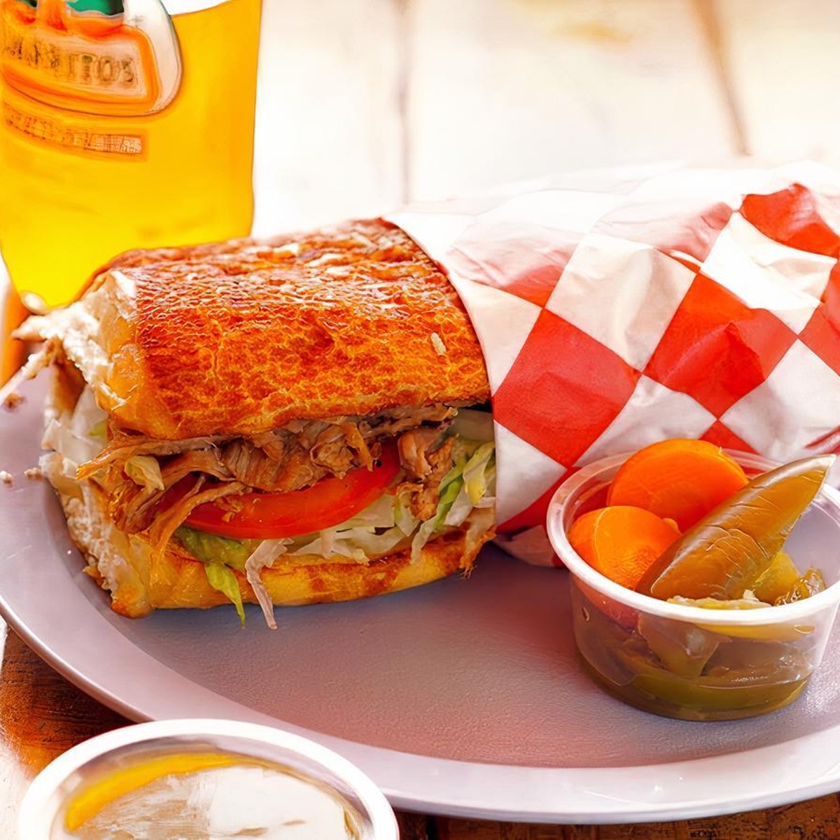 A torta sandwich with a bottle of Jarritos and pickled carrots
